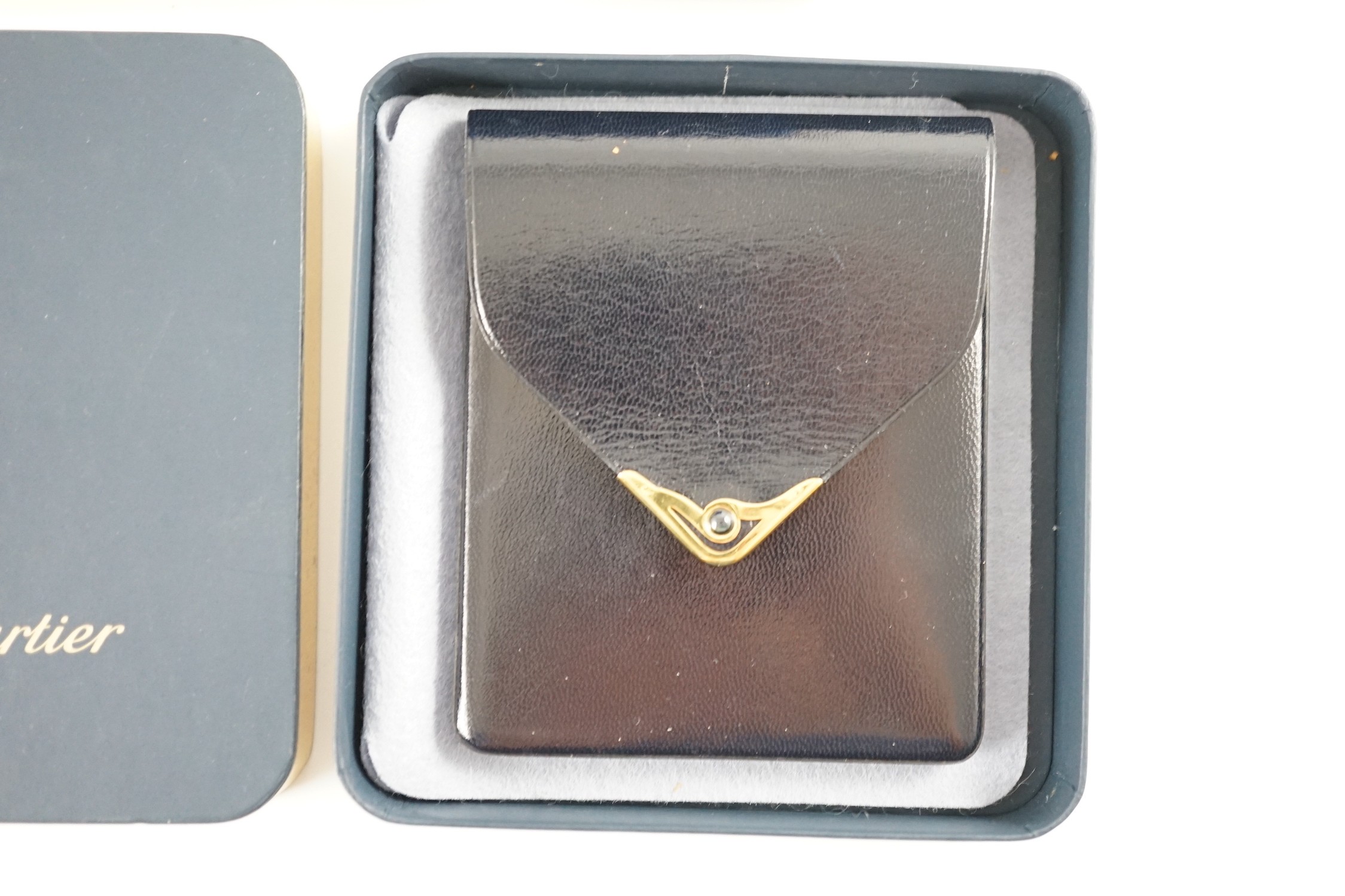 An S de Cartier navy blue leather cigarette case with blue cabochon set clasp, 11 cm., boxed and a Chalana note pen, cased.